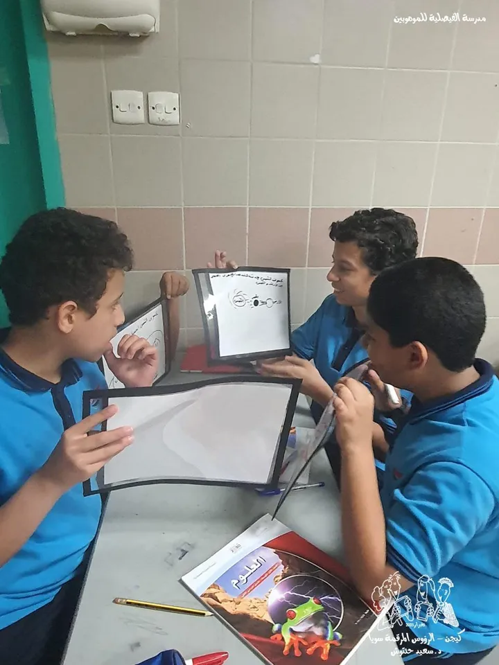 طلاب يعرضون إجاباتهم على سبورات صغيرة أثناء الحصة